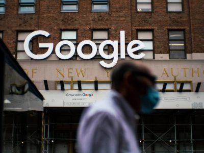 Man in mask passing in front of Google office