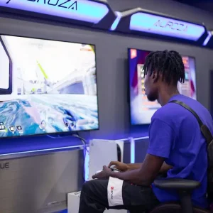 Dark skinned man with dreads playing a video game at Yetra game centre in Accra.