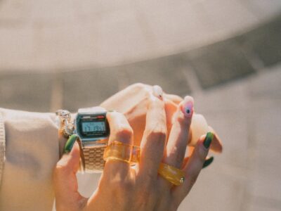 a woman with manicured nails holding a watch